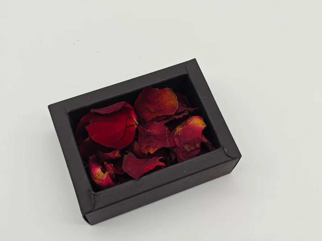 黒い小箱1箱に入った赤いバラのドライ花びらの拡大。深紅やワイン色、黄褐色の部分がある実物。